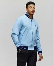 Mens Aldrin Bomber in light blue with navy and light blue striped ribbed collar, cuffs, and hem, featuring a full zip front and an embroidered Psycho Bunny skull logo on the left chest, classic fit. (5)