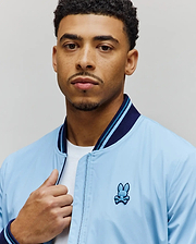 Light blue Mens Aldrin Bomber jacket with a classic fit, featuring a smooth texture, navy and light blue striped ribbed collar and cuffs, and an embroidered Psycho Bunny skull logo on the left chest. (2)