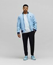Sky Blue Mens Aldrin Bomber jacket, relaxed fit, with navy/white striped ribbed collar, cuffs, hem, and an embroidered Psycho Bunny skull logo on the left chest. (6)