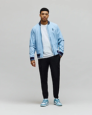 Sky Blue Mens Aldrin Bomber jacket, relaxed fit, with navy/white striped ribbed collar, cuffs, hem, and an embroidered Psycho Bunny skull logo on the left chest. (6)
