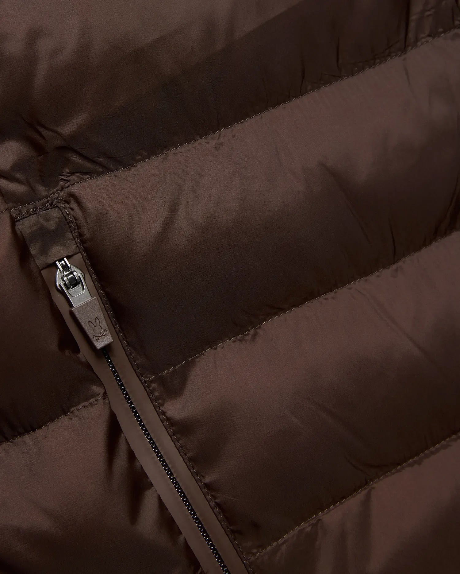Mens Emerik Puffer Jacket in rich brown, crafted from smooth, quilted nylon. Features horizontal puffer channels and a dark grey zipper with a small Psycho Bunny skull logo pull. (6)