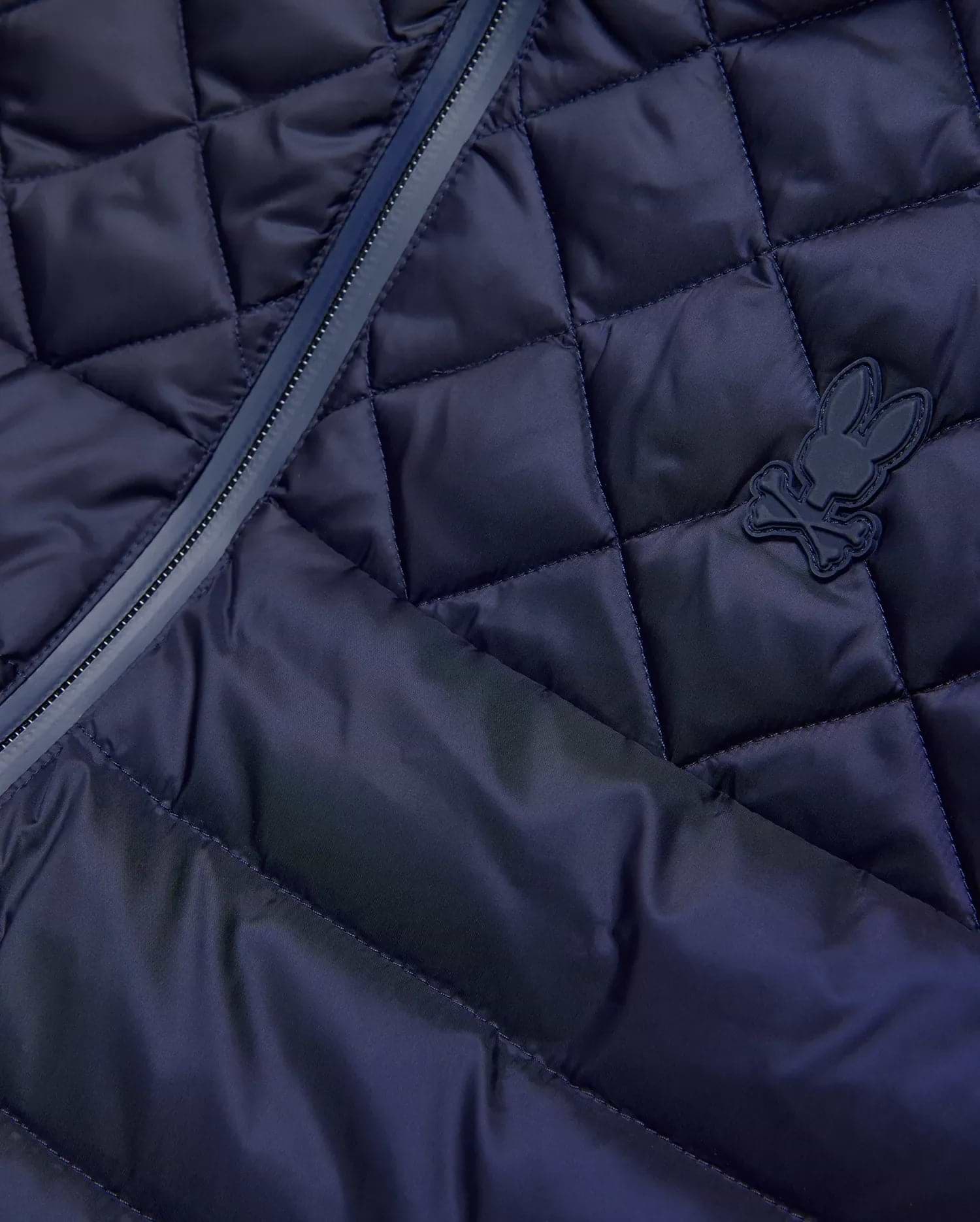Mens Emerik Puffer Vest in navy, featuring a diamond quilted pattern, full-zip closure with dark trim, and a small, matching navy rubberized Psycho Bunny skull logo on the chest. (8)