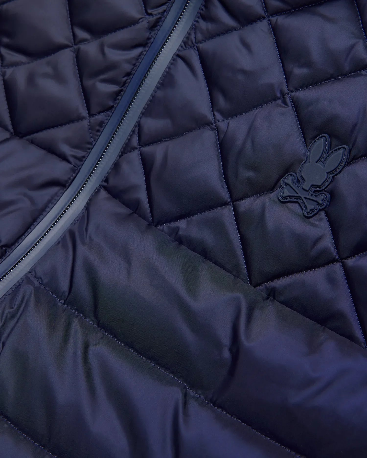 Mens Emerik Puffer Vest in navy, featuring a diamond quilted pattern, full-zip closure with dark trim, and a small, matching navy rubberized Psycho Bunny skull logo on the chest. (8)