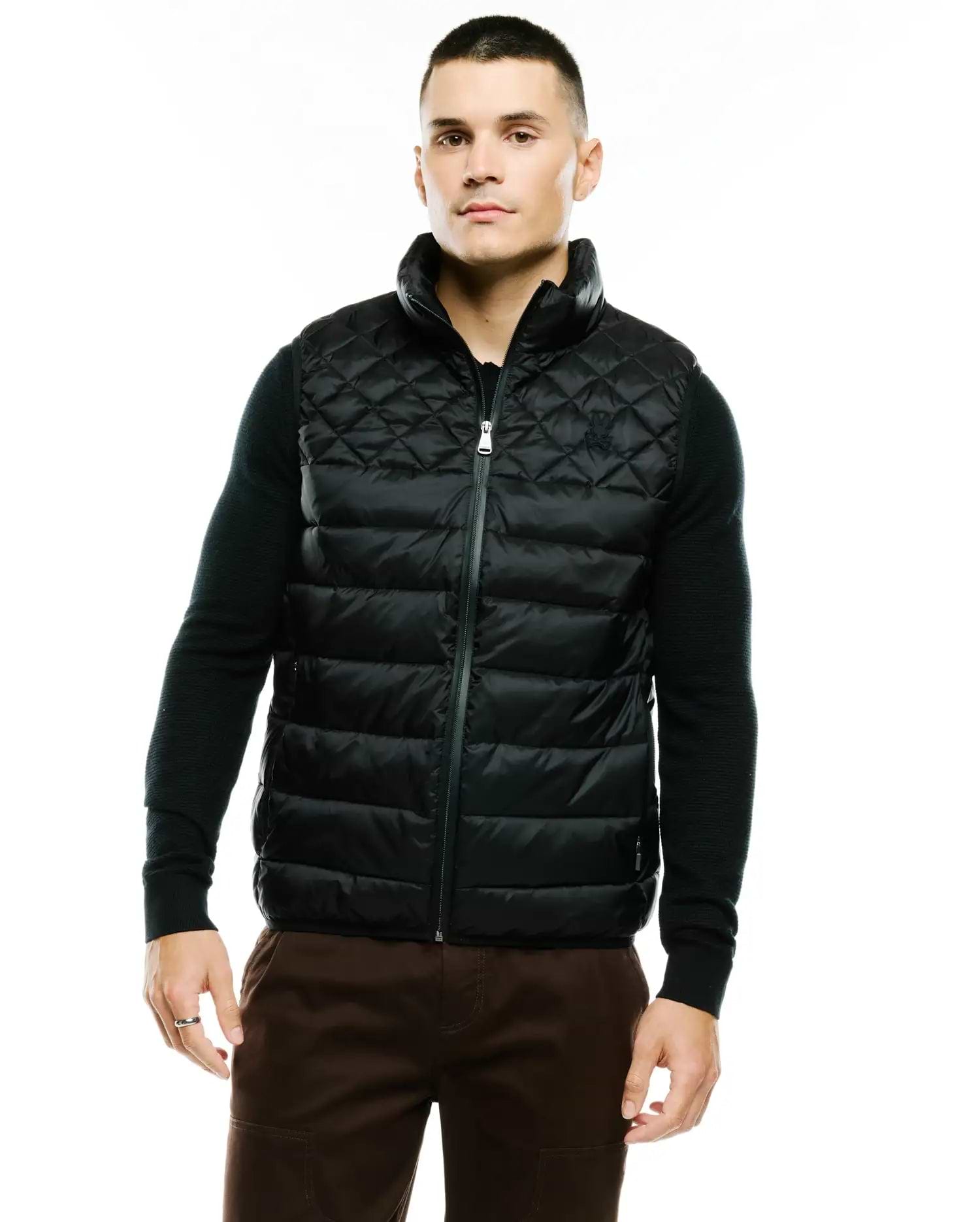 Mens Emerik Quilted Puffer Vest in black, featuring a classic fit, full-zip closure, stand collar, and a small embroidered Psycho Bunny skull logo on the left chest. The vest has a diamond quilted upper and horizontal quilted lower. (1)
