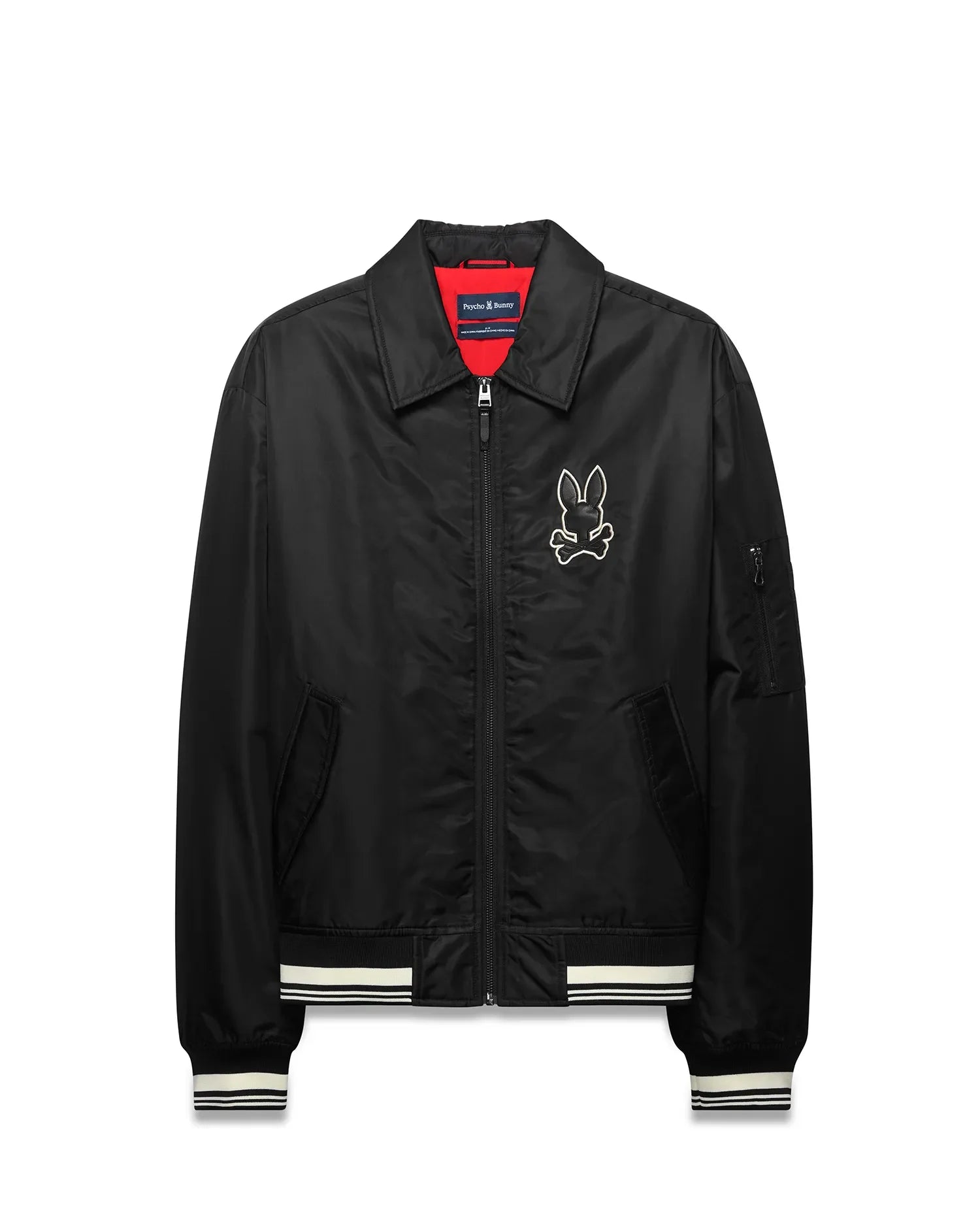 Mens Nathaniel Satin Coach Jacket, black with red lining, featuring a large white embroidered Psycho Bunny skull logo on the chest, white striped ribbed cuffs and hem, and a zippered sleeve pocket. (5)