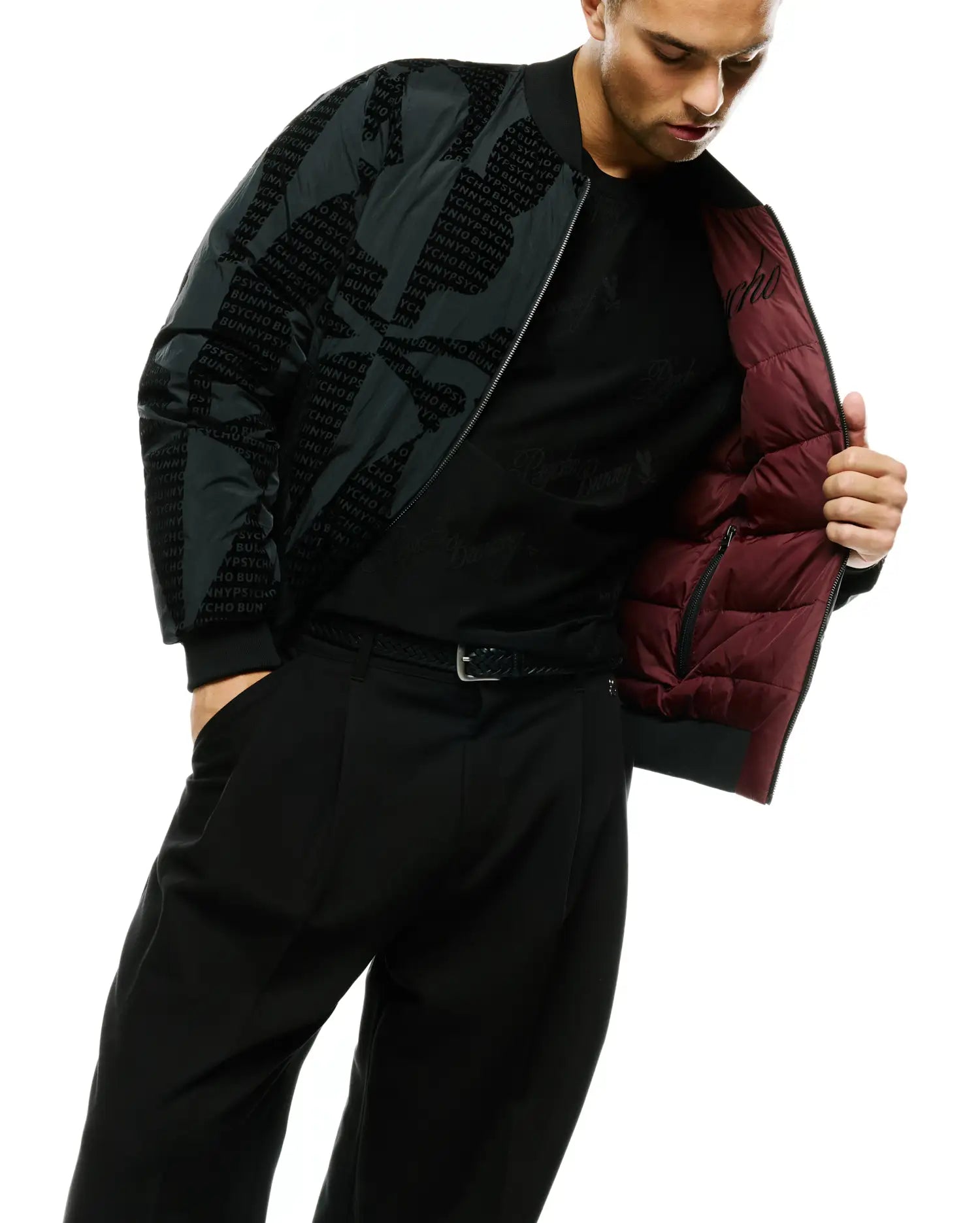MEN'S ANGUS REVERSIBLE BOMBER, a dark green nylon jacket with an all-over tonal Psycho Bunny text pattern, featuring a quilted burgundy lining, ribbed cuffs, and hem. (2)
