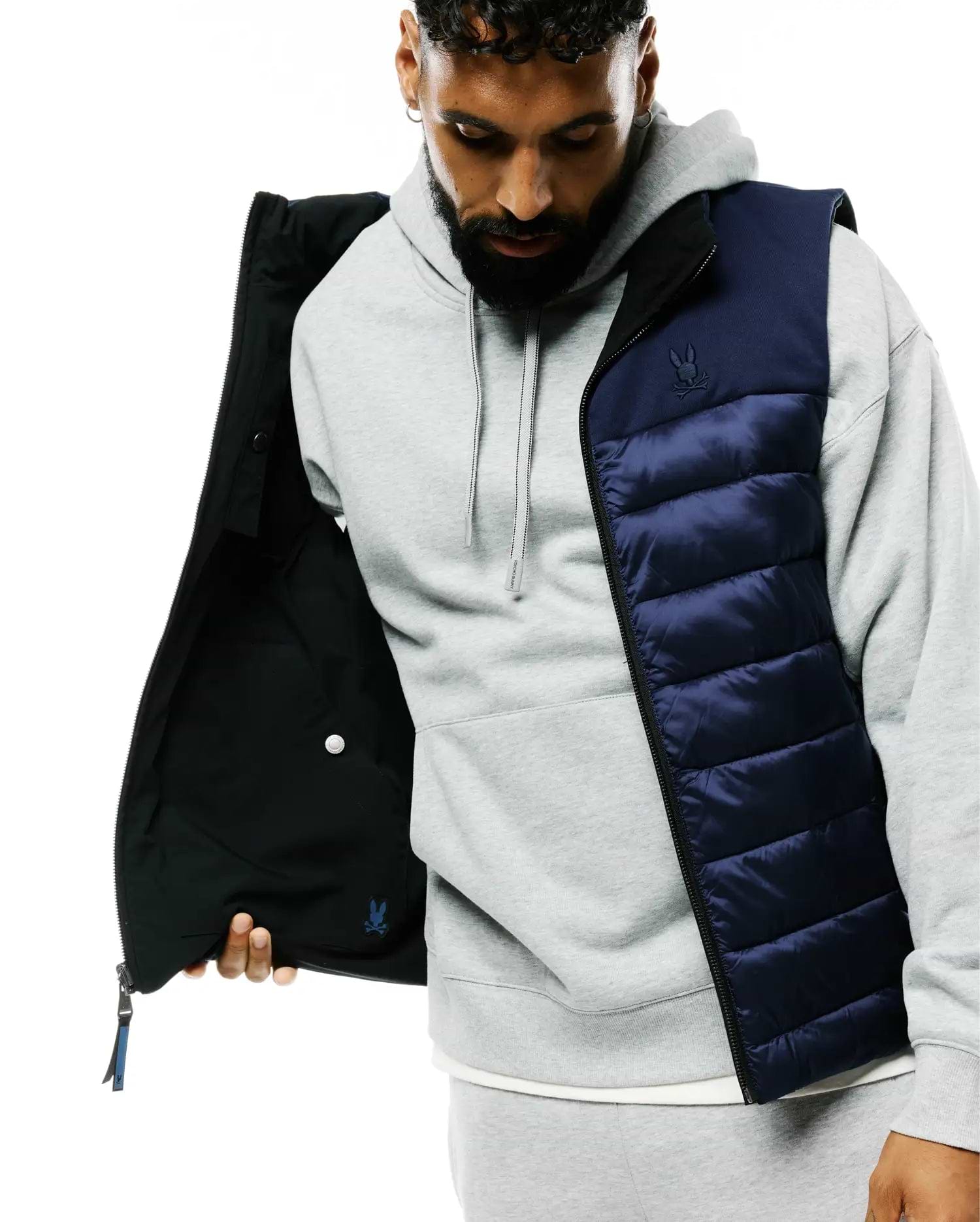 Mens Gordler Reversible Vest, a classic fit navy blue quilted puffer with full zip, reversing to matte black. Embroidered Psycho Bunny skull logo on left chest, smaller blue logo inside.