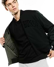 Black Mens Joaquin Mix Media Reversible Bomber jacket with large embroidered BUNNY text on chest, smooth outer fabric, and olive green quilted lining featuring a small Psycho Bunny skull logo.