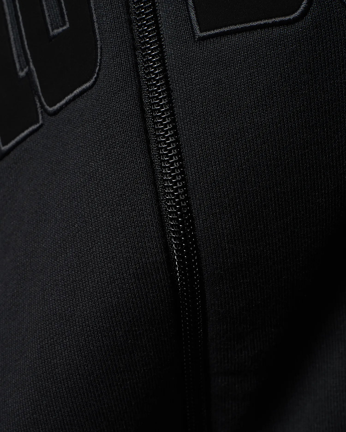 Mens Joaquin Mix Media Reversible Bomber in black, showcasing large raised black letters with a subtle grey outline on a smooth knit fabric, alongside a black front zipper.