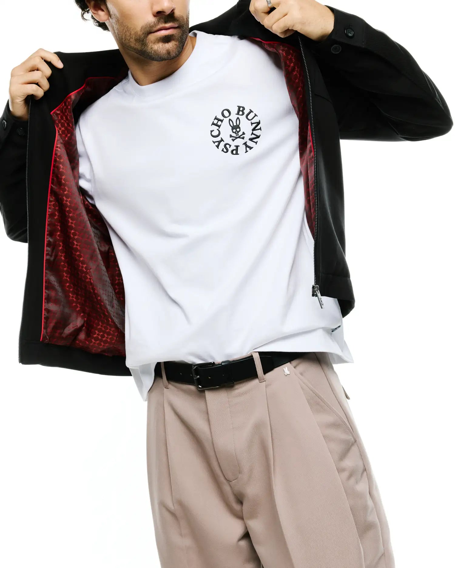 Men's Wayde Twill Overshirt in black, featuring a full zip, buttoned cuffs, and a vibrant red patterned lining. Layered over a white jersey t-shirt with a large central black Psycho Bunny skull logo. (3)