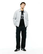 Mens Marc Textured Overshirt in light grey, featuring a subtle textured fabric, classic collar, and a single chest pocket, worn over a black t-shirt with a large white Psycho Bunny skull and crossbones graphic.
