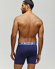 A man with short dark hair stands shirtless, facing away, wearing navy blue Psycho Bunny MENS SINGLE BOXER BRIEF - MO1400010 with a light blue logo waistband and breathable knit Pima cotton for comfort and style. (3)
