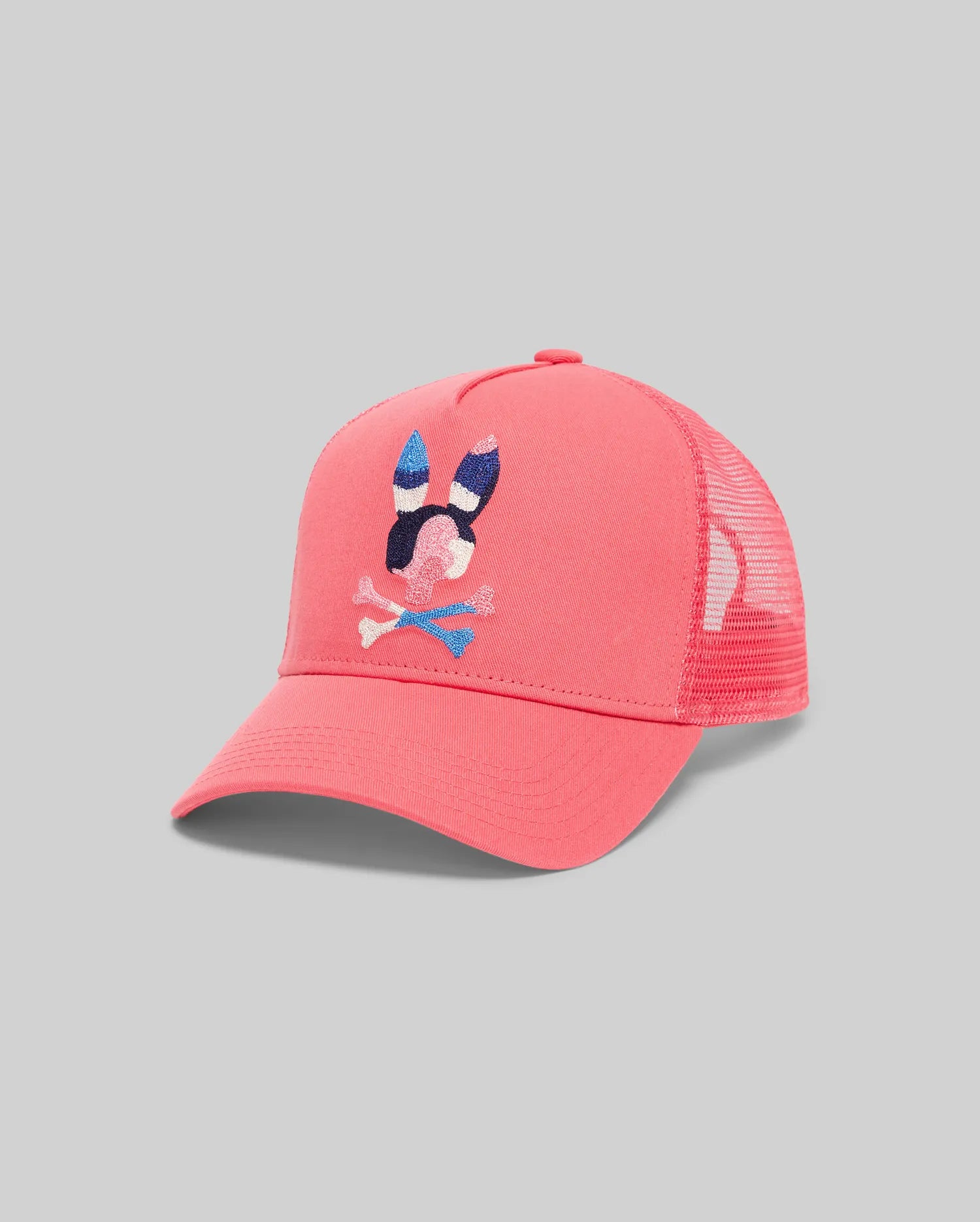 Mens Ara Trucker Cap in vibrant coral with a large, intricately embroidered Psycho Bunny skull logo in blue, white, and black on the cotton twill front panel, featuring a breathable mesh back. (2)