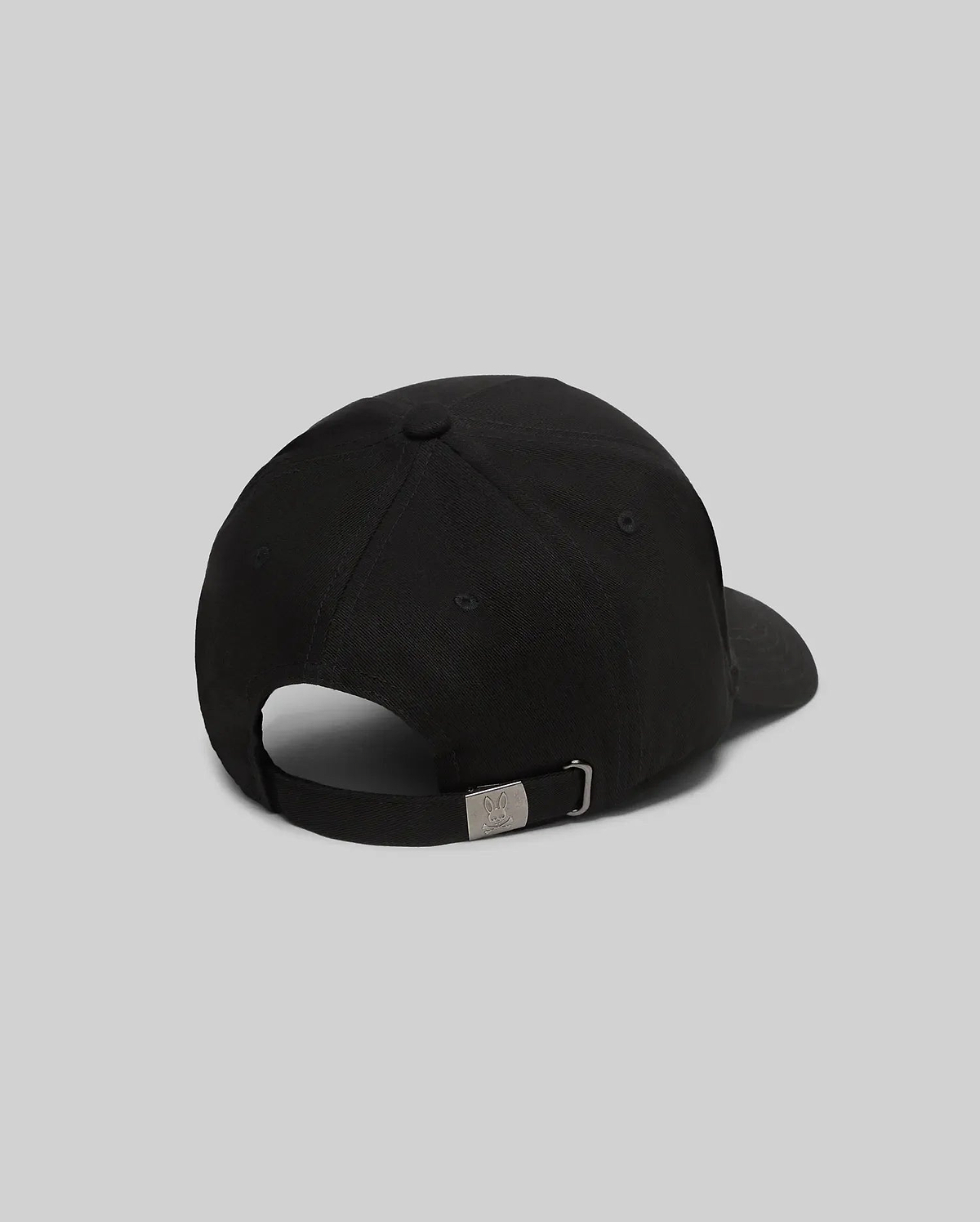 Mens Oscar Trucker Cap, a sleek black baseball cap with a smooth fabric finish and an adjustable back strap featuring a gunmetal buckle engraved with the iconic Psycho Bunny skull logo.