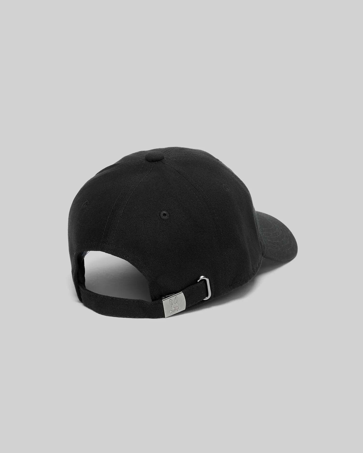 Black Mens Jimmy Baseball Cap with a smooth twill texture, featuring an adjustable strap and a small metallic Psycho Bunny skull logo on the silver buckle at the back.