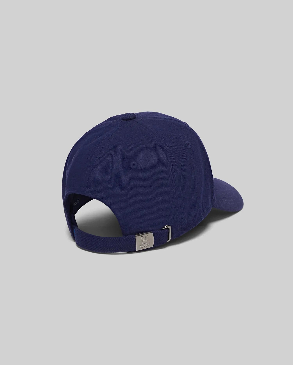 Navy blue Mens Jimmy Baseball Cap crafted from smooth cotton twill, featuring an adjustable strap and a silver-tone metal buckle with a small embossed Psycho Bunny skull logo.