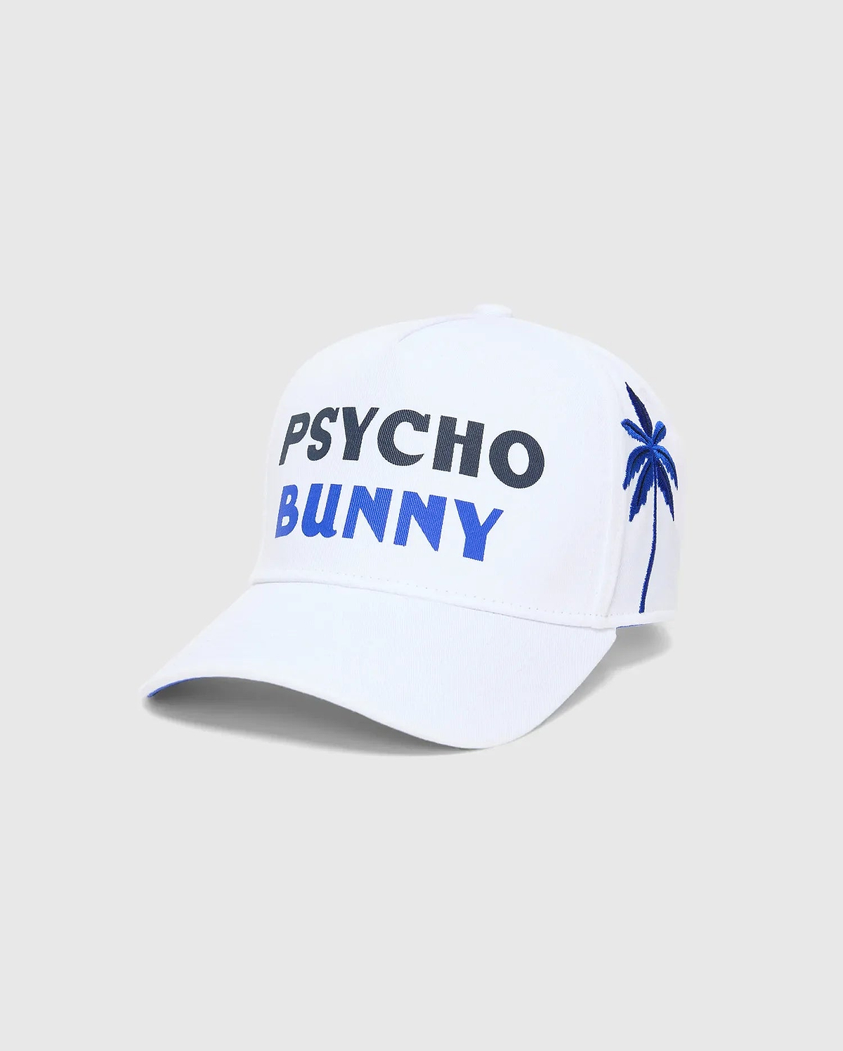 White Mens Brad Trucker Cap featuring large embroidered PSYCHO in dark blue and BUNNY in bright blue on the front, with an embroidered blue palm tree on the side.