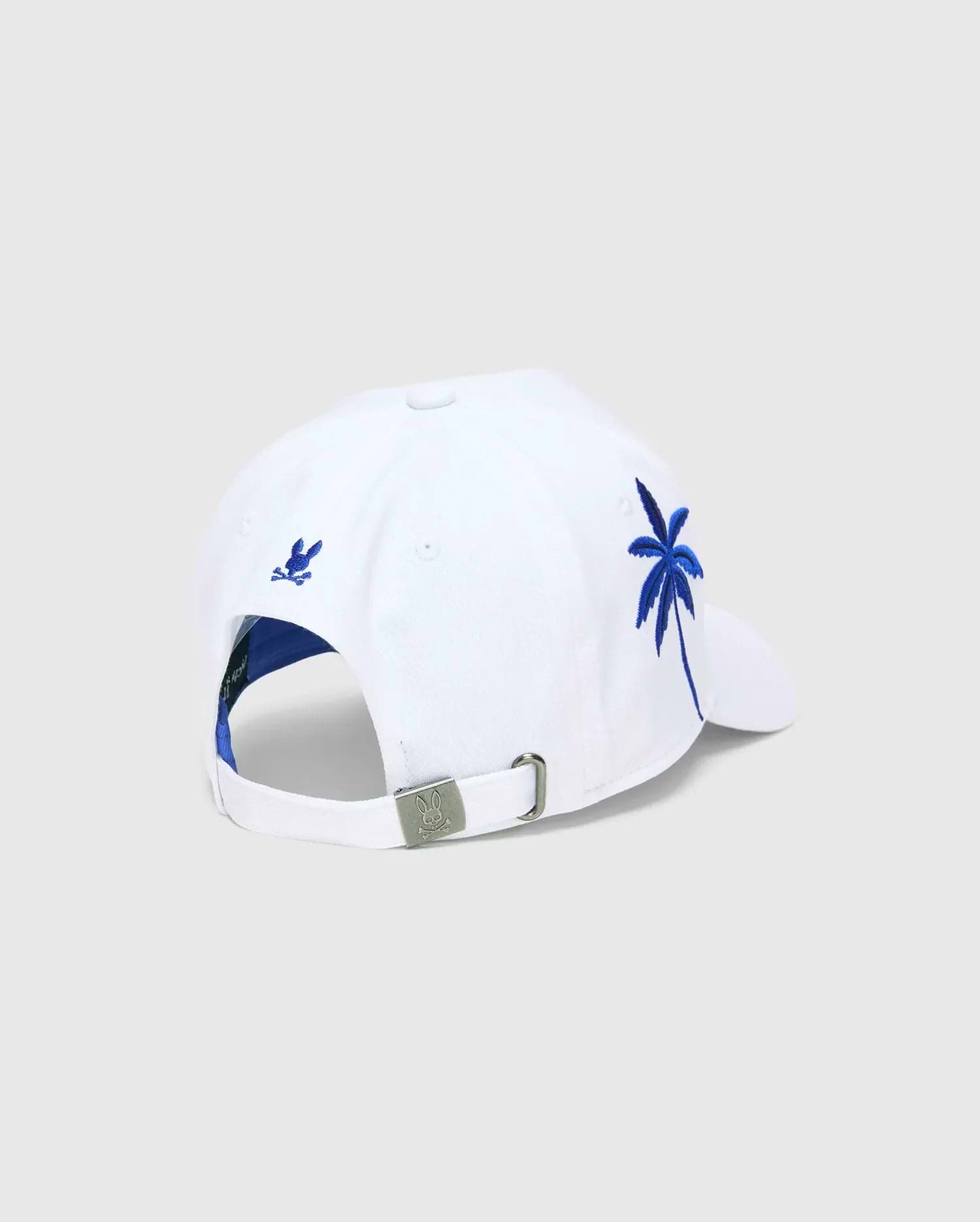 White Mens Brad Trucker Cap with blue interior, featuring a vibrant blue embroidered palm tree on the side, a small blue embroidered Psycho Bunny skull on the back, and a branded metal buckle.