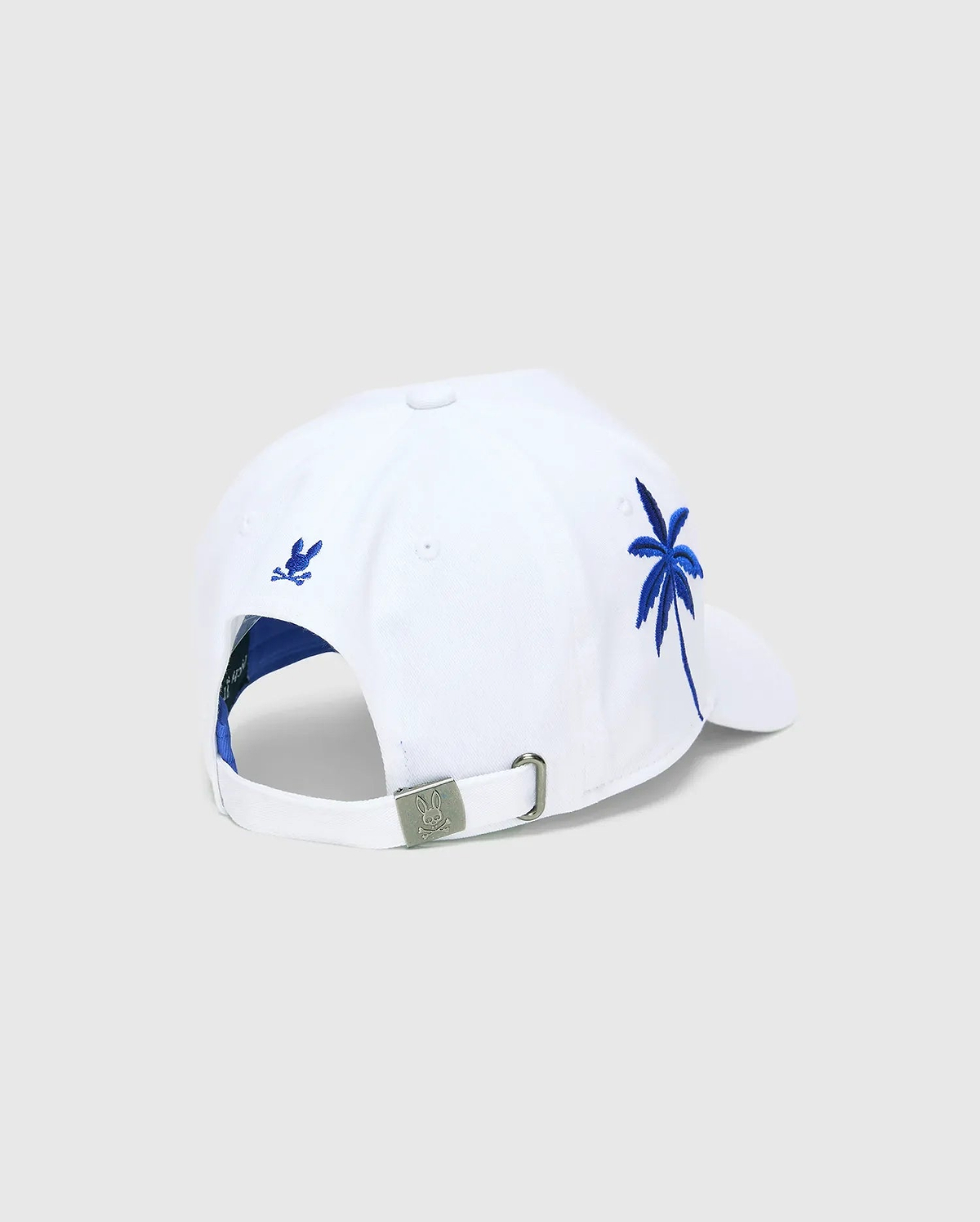White Mens Brad Trucker Cap with blue interior, featuring a vibrant blue embroidered palm tree on the side, a small blue embroidered Psycho Bunny skull on the back, and a branded metal buckle.