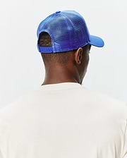 Mens Tobias Trucker Cap in vibrant royal blue, featuring a mesh back, solid front panel, curved brim, and adjustable snap closure, worn with a cream classic fit jersey knit t-shirt.
