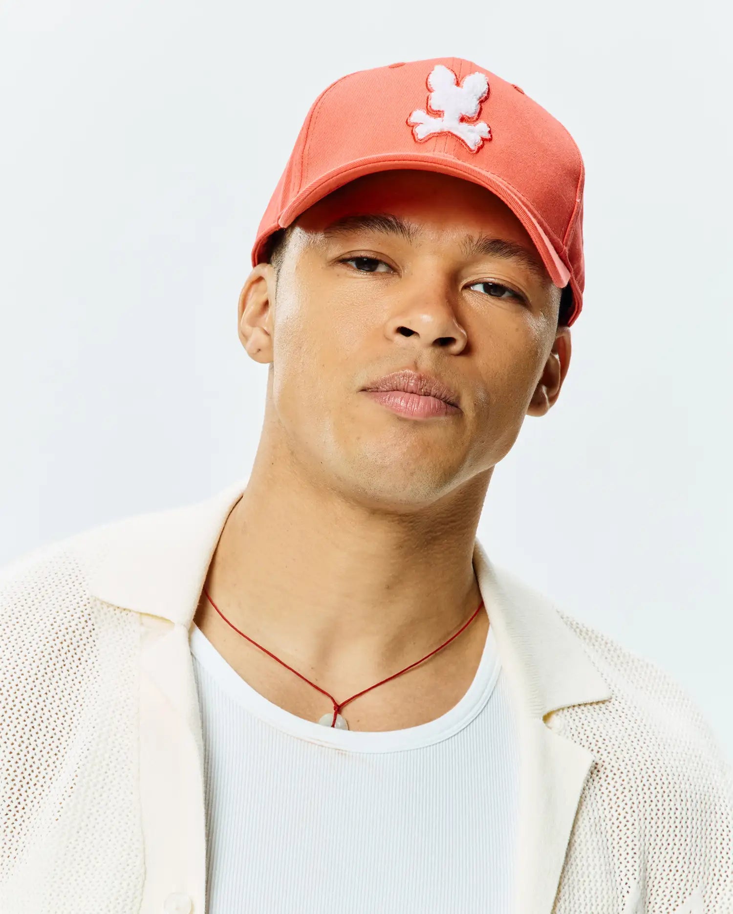Mens Craig Baseball Cap in vibrant coral, featuring a large, prominent white embroidered Psycho Bunny skull logo on the front, crafted from smooth twill fabric.
