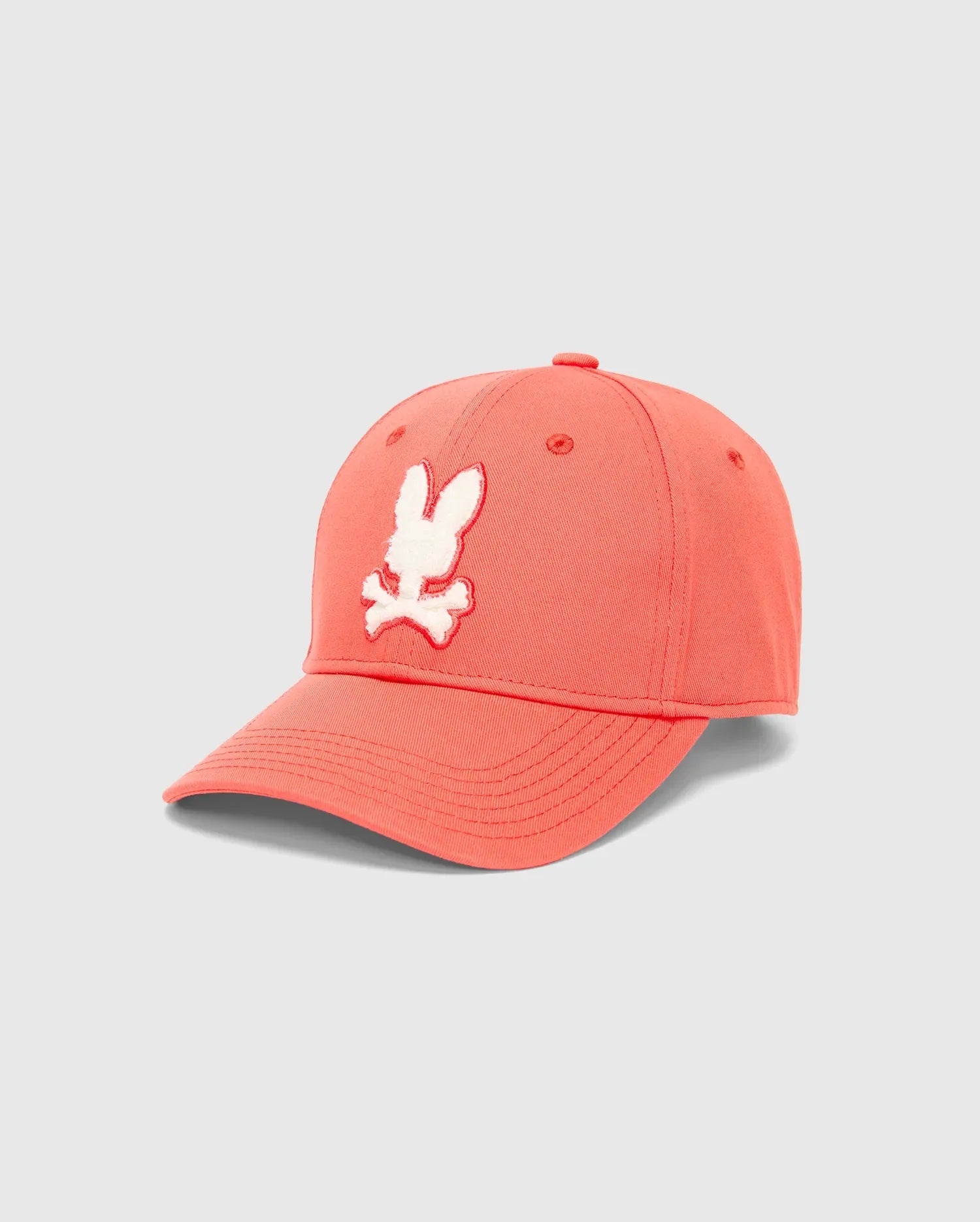 Mens Craig Baseball Cap in vibrant coral cotton twill, featuring a large, raised white embroidered Psycho Bunny skull logo centered on the front, with matching eyelets.