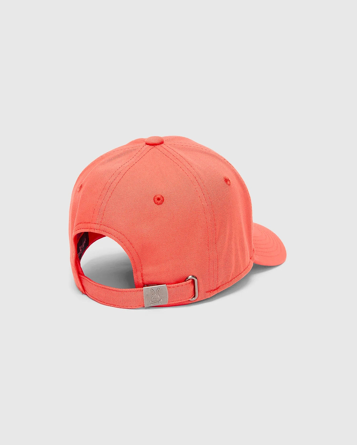 Mens Craig Baseball Cap in vibrant coral twill, featuring an adjustable strap with a silver-tone metal buckle engraved with the iconic Psycho Bunny skull logo.