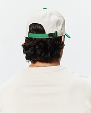 Mens Craig Baseball Cap in cream cotton twill with a green brim and adjustable strap featuring a small Psycho Bunny skull logo on the metal buckle.