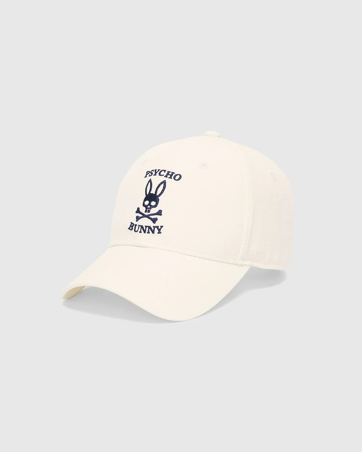 Mens Hubert Baseball Cap in cream, featuring a prominent navy blue embroidered Psycho Bunny skull logo and text on the front, with textured side panels.