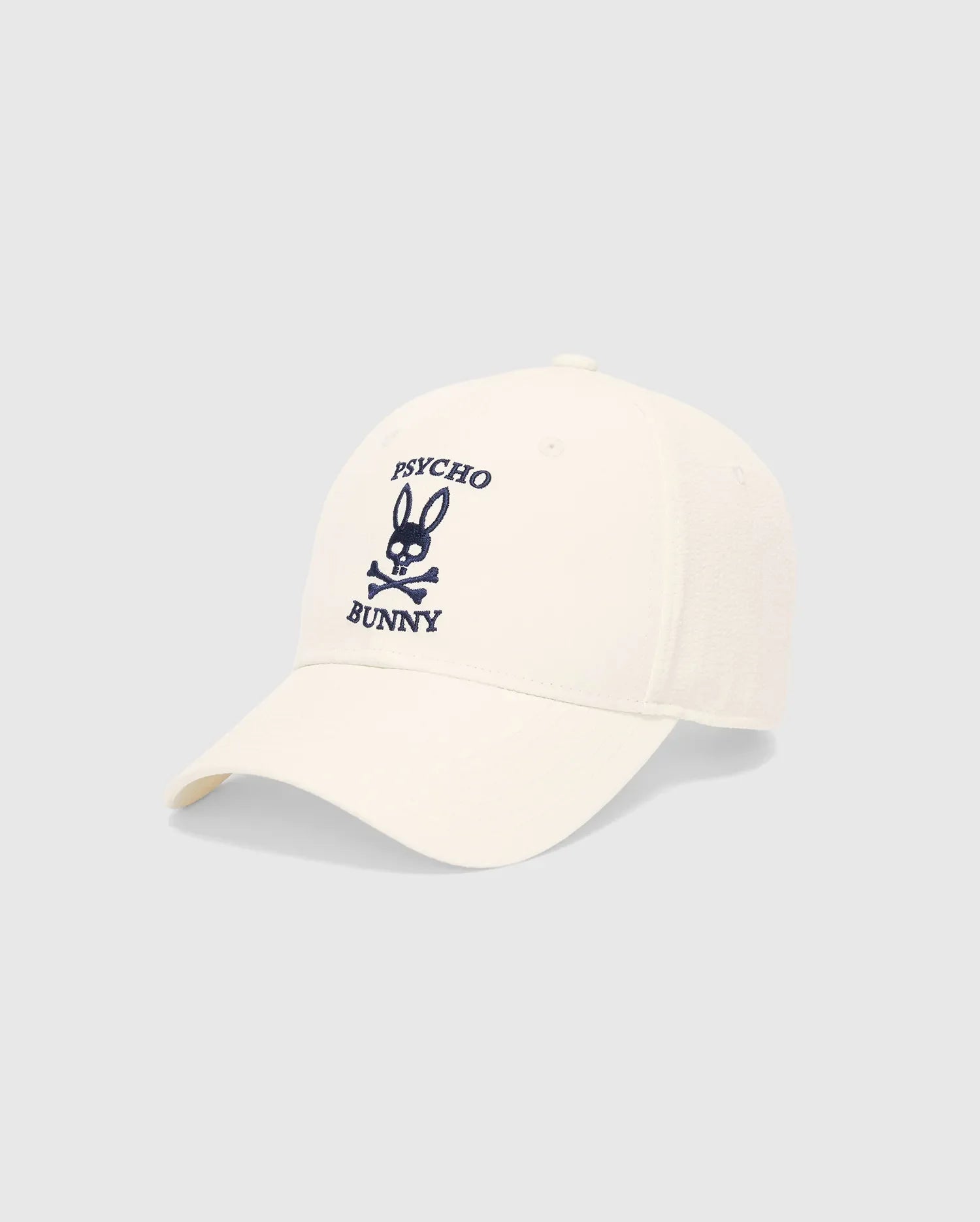 Mens Hubert Baseball Cap in cream, featuring a prominent navy blue embroidered Psycho Bunny skull logo and text on the front, with textured side panels.