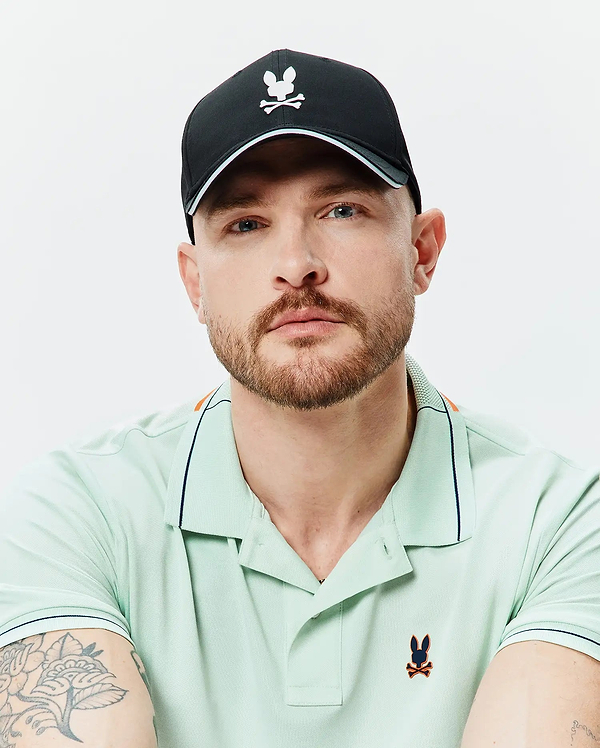 Mens Blaze Sport Cap, black cap, white Psycho Bunny skull logo, light blue brim trim. Light green pique polo, dark blue tipping, orange shoulder stripe, embroidered Psycho Bunny logo.