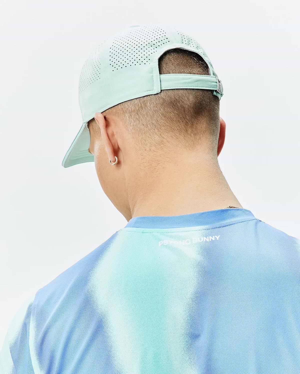 Mens Blaze Sport Cap in mint green with perforated panels and a blue and aqua tie-dye mesh t-shirt featuring a small white Psycho Bunny text logo on the back. (3)
