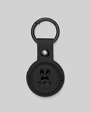 The Psycho Bunny MENS AIR TAG HOLDER - MO1700017 features black leather, a circular design, embossed Bunny logo with crossbones on the front, and a metal keyring—ideal for stylishly securing your keys or luggage tag.