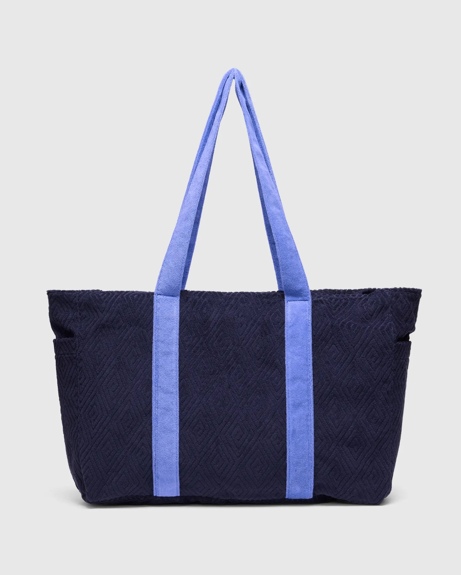 Tristan Towel Tote, a premium navy blue bag featuring a distinctive quilted diamond pattern throughout its plush towel-textured body, complemented by bold periwinkle blue towel-textured shoulder straps.