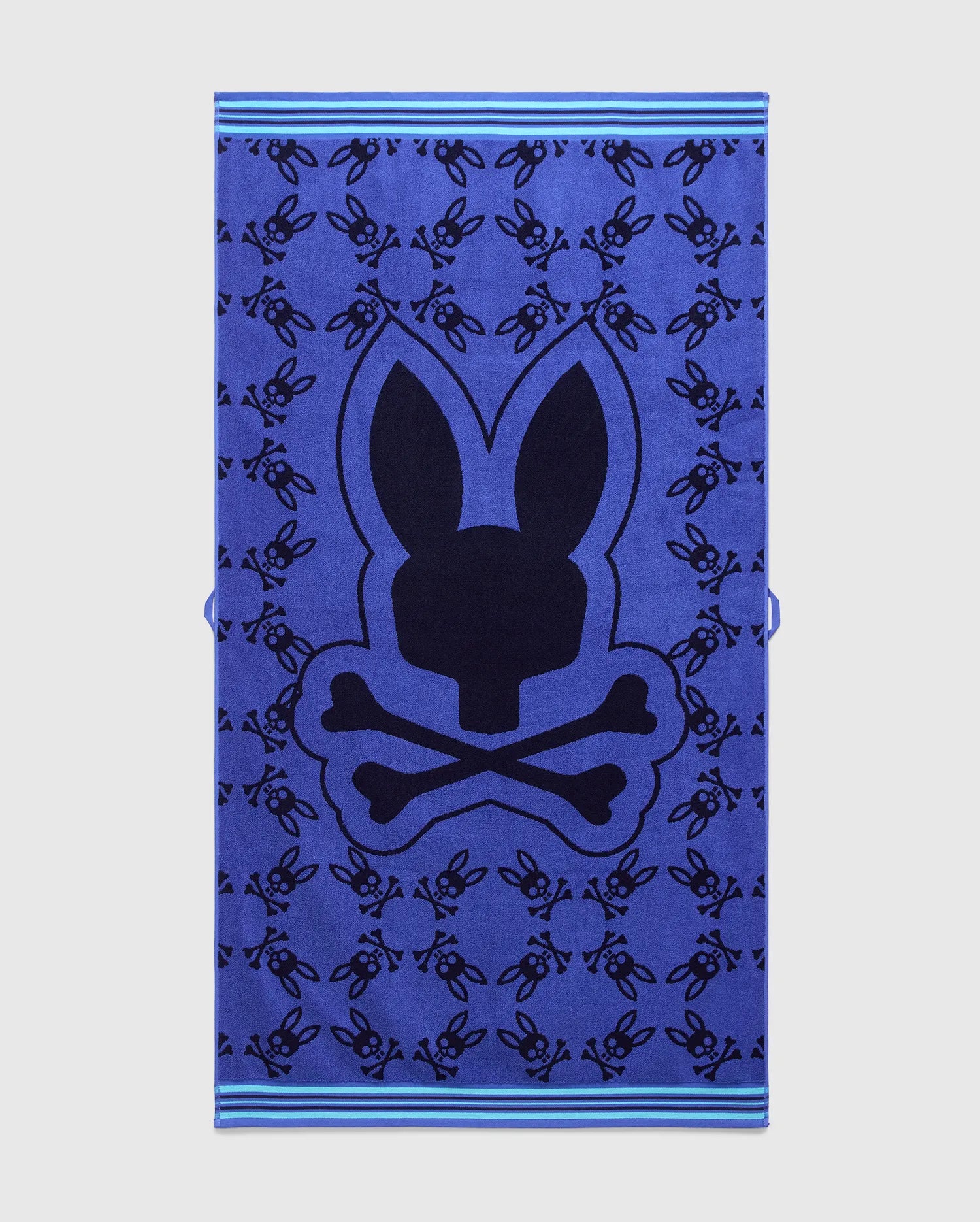 Vibrant blue All Over Bunny Towel featuring a large central dark blue Psycho Bunny skull logo, an all-over pattern of smaller dark blue bunny skulls, and light blue striped borders. (1)