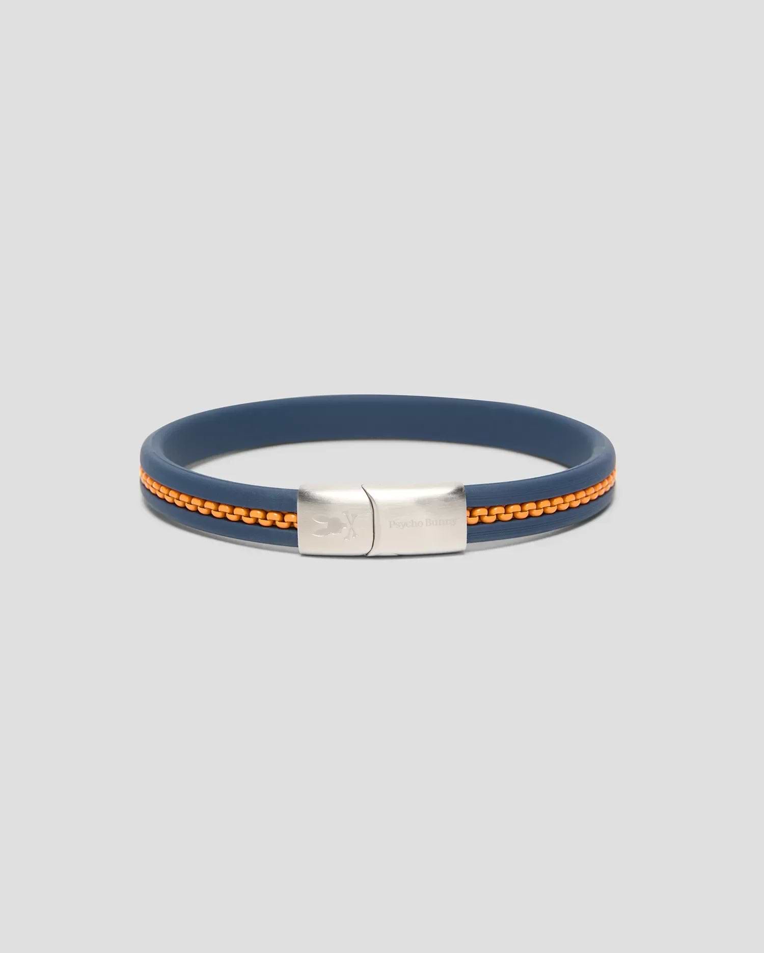Mens Link Rubber Bracelet in navy blue rubber with an embedded orange chain detail, featuring a silver-toned metal clasp engraved with the Psycho Bunny skull logo and text. (1)