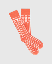 Mens Brad Dress Sock in vibrant coral knit, featuring a white scalloped pattern with alternating Psycho Bunny skull logos and palm trees on the cuff, transitioning to vertical white stripes.