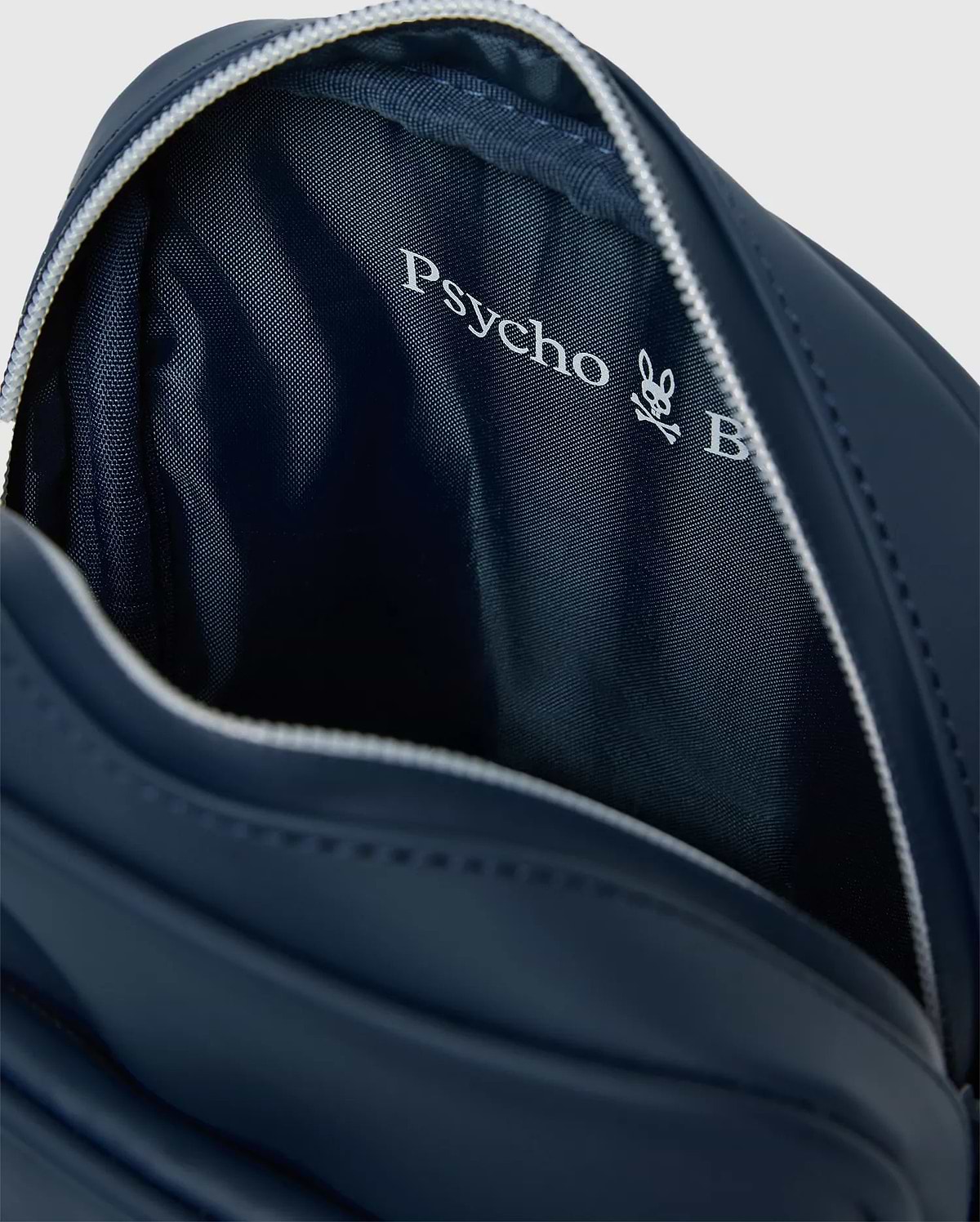 Classic Bunny Messenger Bag in navy blue, featuring a smooth exterior, white zipper, and a textured interior lining with a prominent white Psycho Bunny logo.
