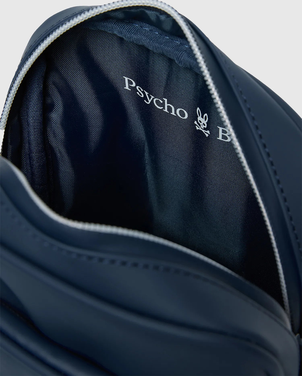 Classic Bunny Messenger Bag in navy blue, featuring a smooth exterior, white zipper, and a textured interior lining with a prominent white Psycho Bunny logo.