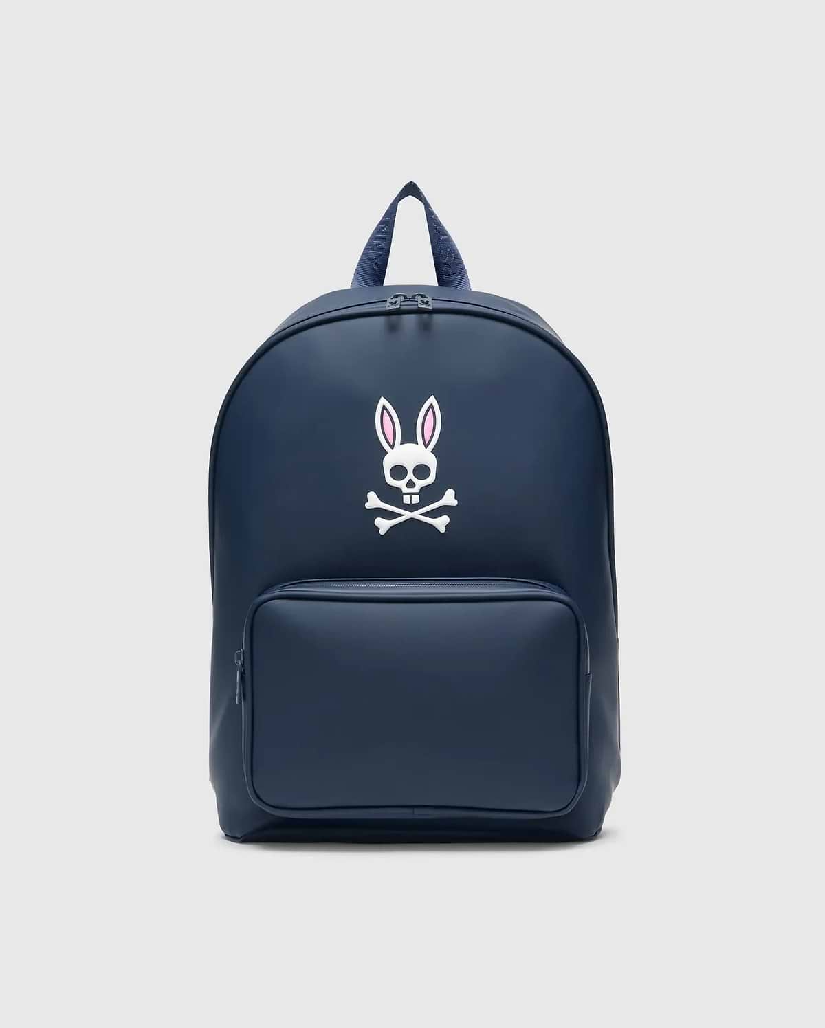 Classic Bunny Backpack in navy blue with a smooth matte finish, featuring a large white and pink Psycho Bunny skull logo centered on the front and a zippered front pocket.