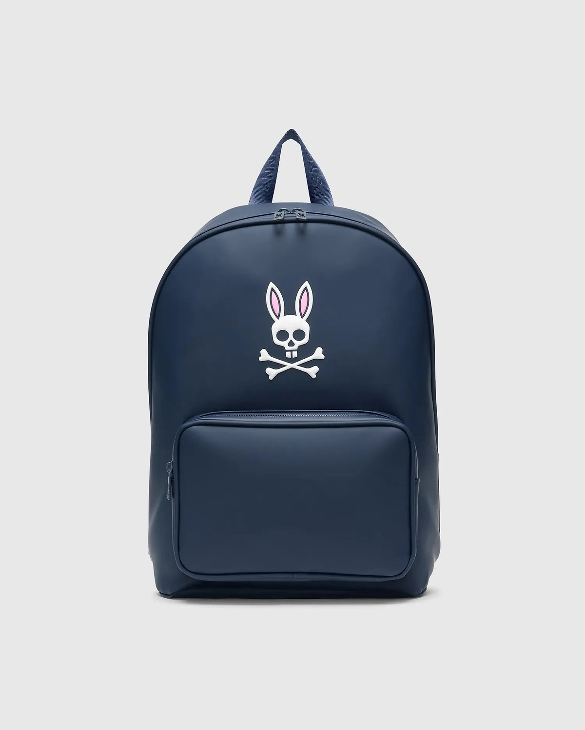 Classic Bunny Backpack in navy blue with a smooth matte finish, featuring a large white and pink Psycho Bunny skull logo centered on the front and a zippered front pocket.