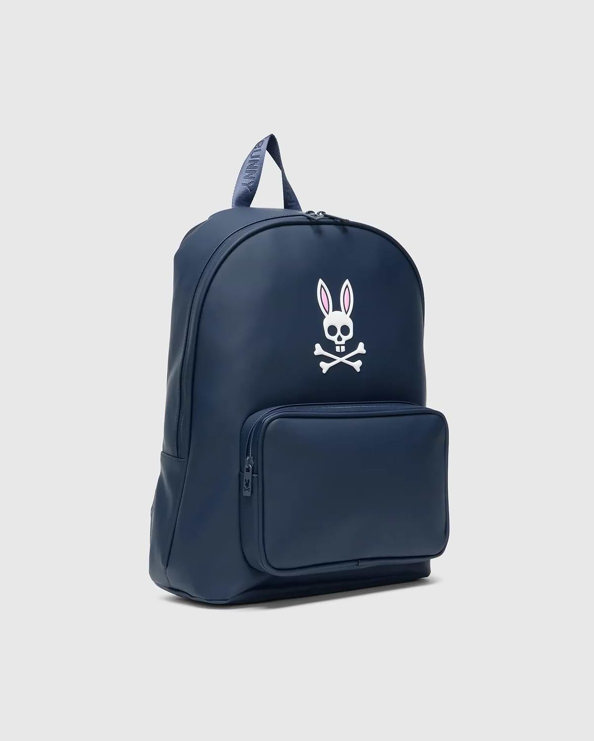 Classic Bunny Backpack in navy blue, featuring a large white and pink Psycho Bunny skull logo on the front, a zippered pocket, and a branded top handle. Smooth finish.