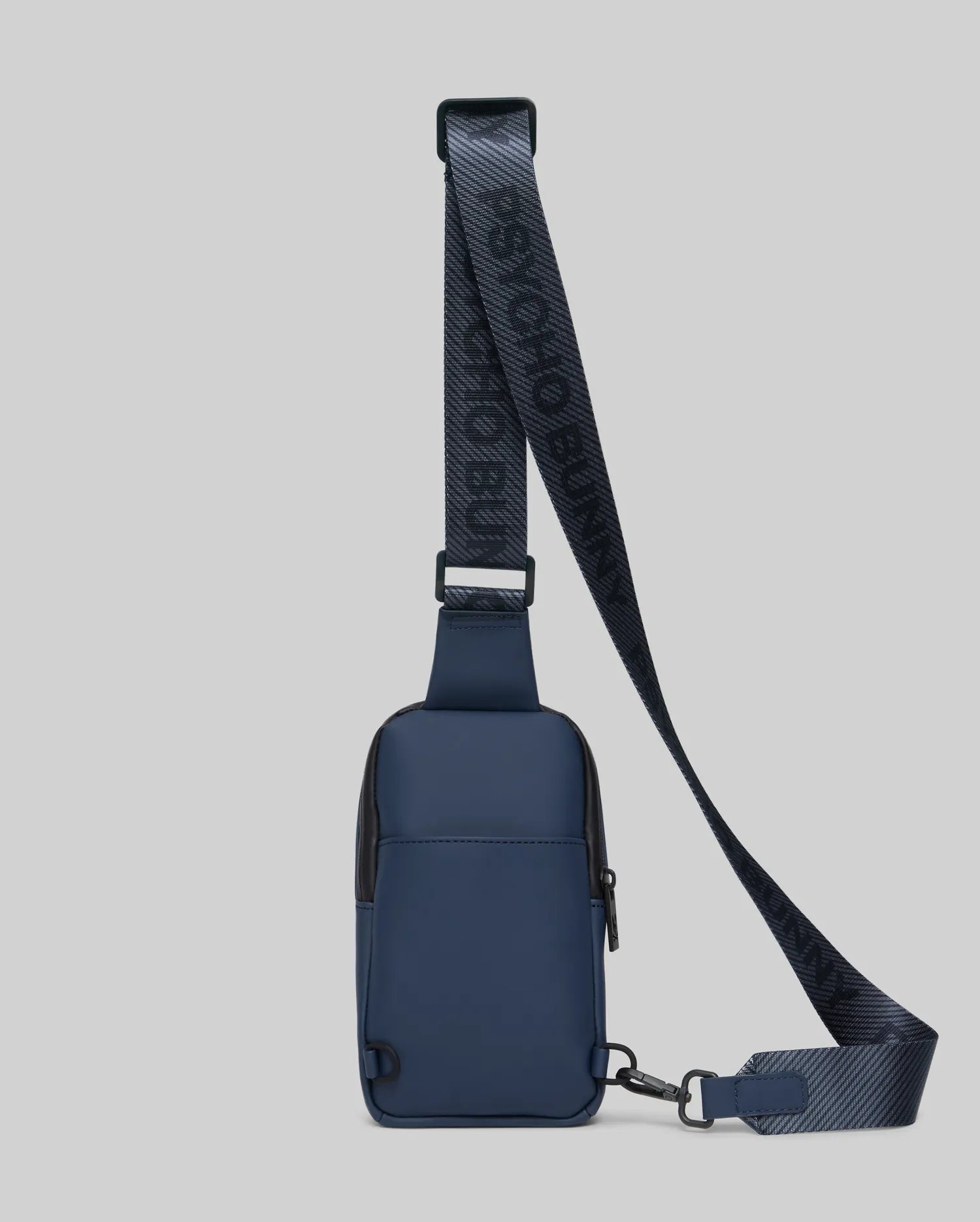 Mens Rubberized Crossbody in deep navy blue with black accents, featuring a smooth rubberized texture and a prominent woven strap displaying repeating Psycho Bunny branding. (3)