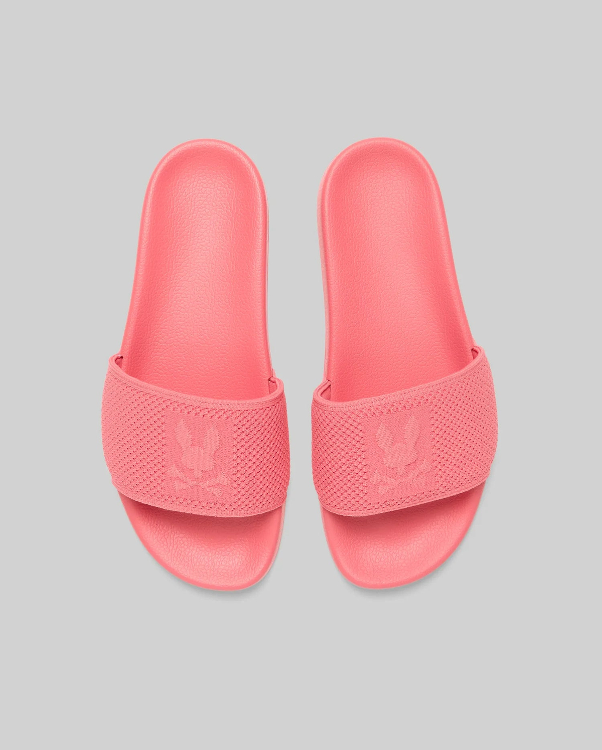 Mens Knit Slides in vibrant coral pink, featuring a textured knit strap with a prominent debossed Psycho Bunny skull logo, and a matching textured rubber sole for comfort. (3)