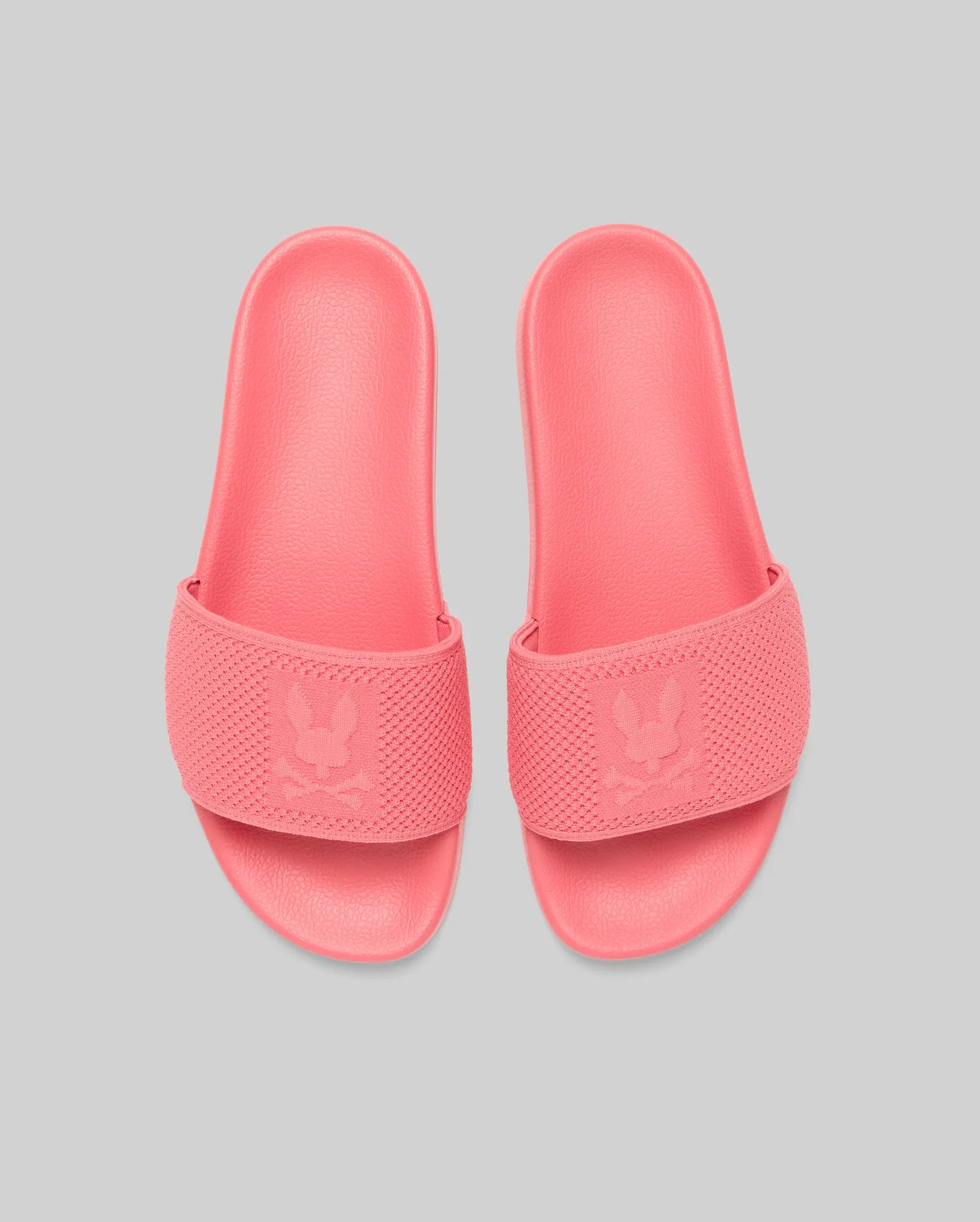 Mens Knit Slides in vibrant coral pink, featuring a textured knit strap with a prominent debossed Psycho Bunny skull logo, and a matching textured rubber sole for comfort. (3)