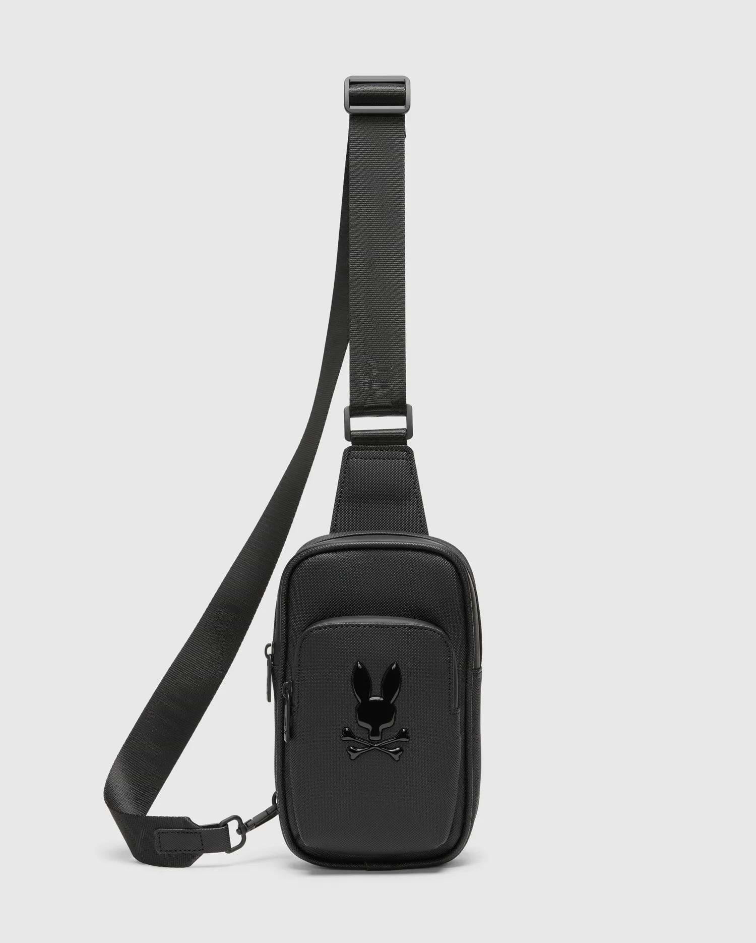 Black Crossbody Bag crafted from a refined Saffiano-style textured material, featuring a prominent glossy black Psycho Bunny skull logo on the front pocket and a durable adjustable strap. (1)