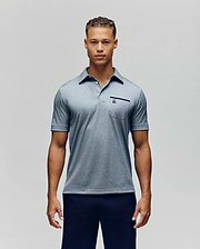 A man poses against a plain background, wearing the Psycho Bunny MENS HADLEY PERFORMANCE PIQUE POLO - MT0100021 in light blue with a buttoned collar and small chest pocket, paired with dark pants, looking at the camera with a neutral expression. (1)