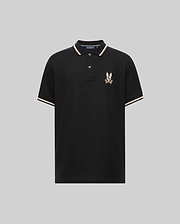 The Psycho Bunny MENS WADE PIQUE POLO (MT0100044) is a black Pima cotton polo for men, featuring white and beige colorblock trim on the collar and sleeves, plus an embroidered eagle crest logo on the left chest. Displayed on a plain gray background.