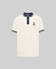 The Psycho Bunny MENS WADE PIQUE POLO (MT0100044) is a white colorblock polo with navy blue collar and sleeve cuffs, plus an embroidered bunny patch on the left chest.
