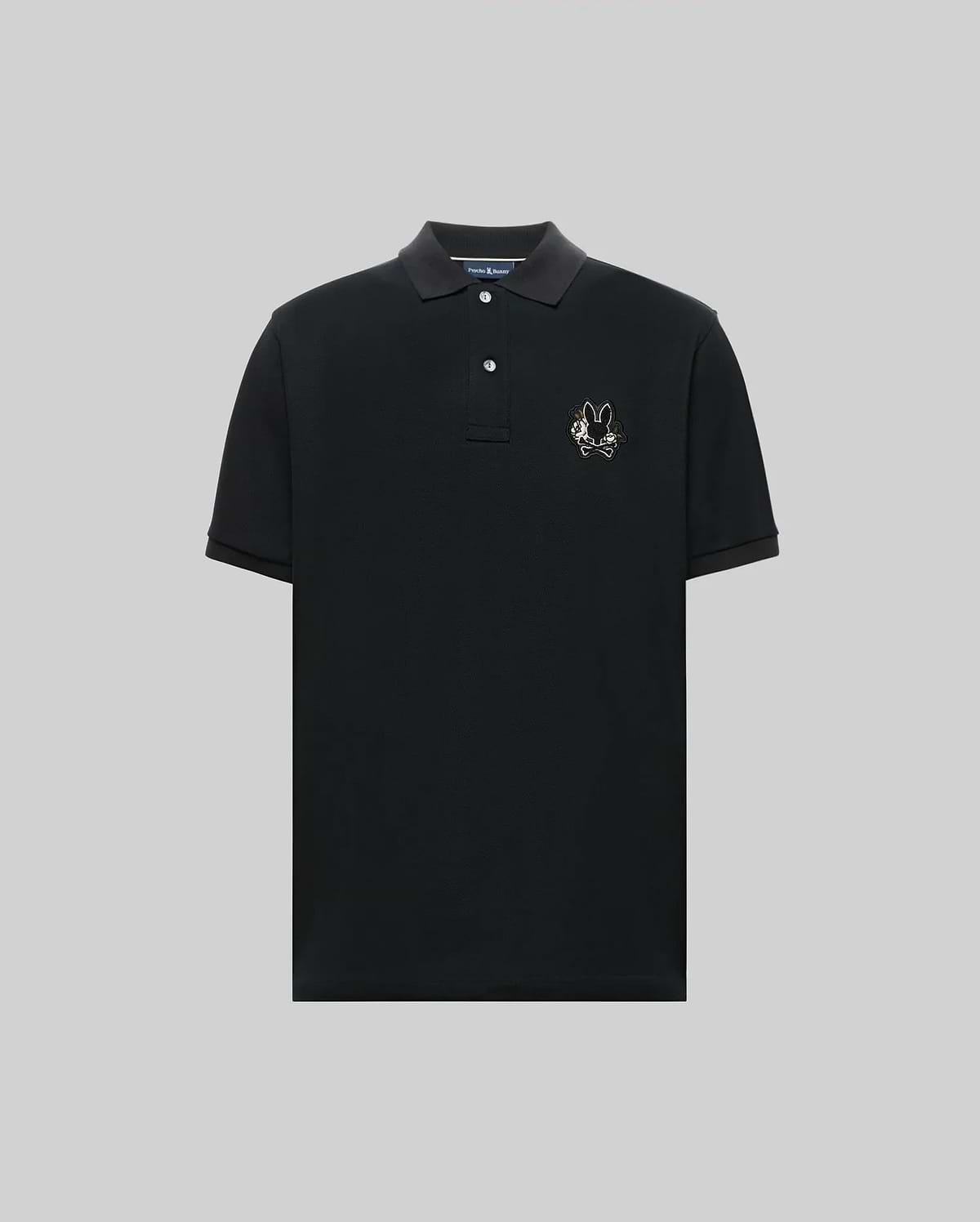 The Psycho Bunny MENS AUGUSTE PIQUE POLO SHIRT (MT0100051) is a black, short-sleeved collared polo with three buttons and an embroidered chenille bunny patch on the left chest, shown against a plain gray background. (5)